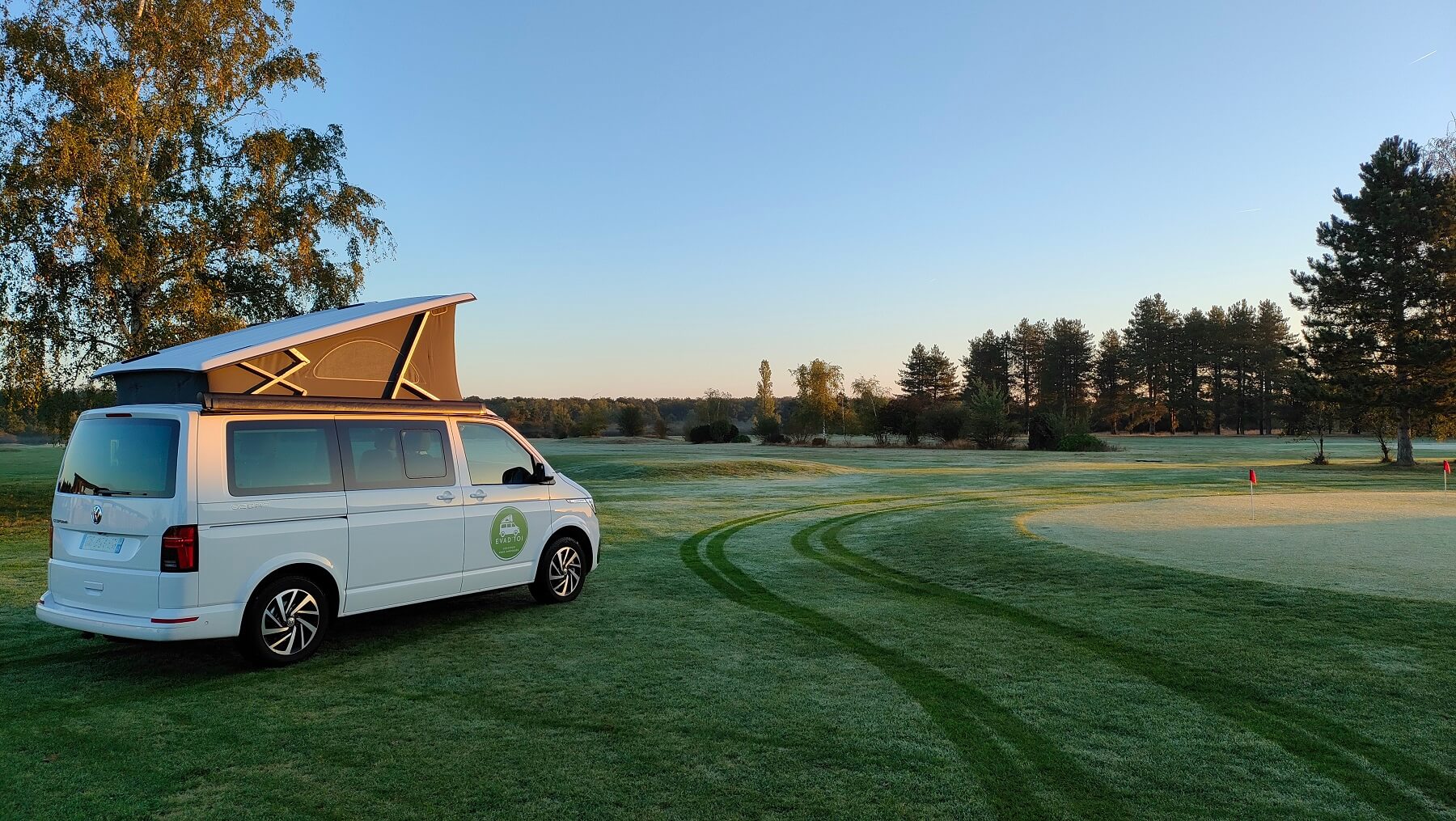 Location Van VW California EVAD'TOI sur un green de golf au levé du soleil avec rosée